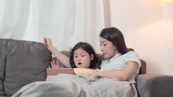 Portrait Happy Daughter playing smartphone with her mother on sofa in living room alt