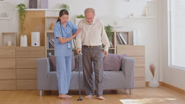 Beautiful doctor helping old man at clinic. Holding a senior patient with walking stick. Elder man u alt