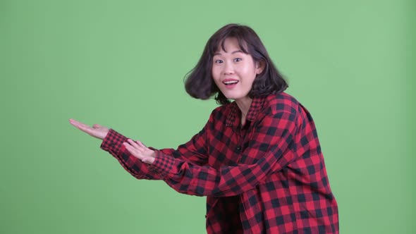 Happy Asian Hipster Woman Showing Something and Looking Surprised alt