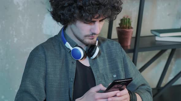 Serious Young Man Sitting in His Home Office and Texting to His Friends alt
