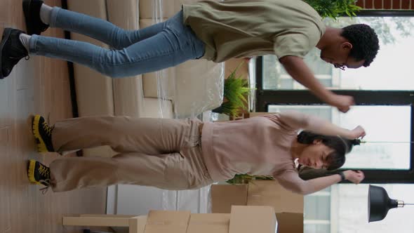 Vertical Video Cheerful Couple Dancing in New Apartment Celebrating Relocation alt