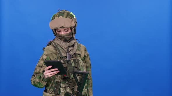 Modern Soldier Female in Camouflage on the Blue Chroma Key Military Engineer Uses a Digital Screen alt