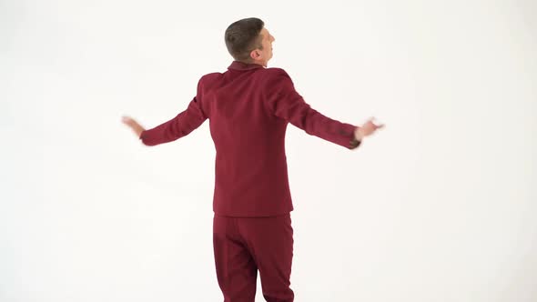 fun showman in red suit is waving his arms and spinning around himself on a white background alt