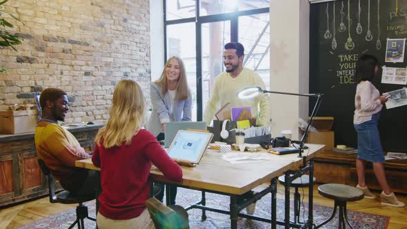 Group of Young Multiethnic Designers Smiling and Discussing Ideas in Office