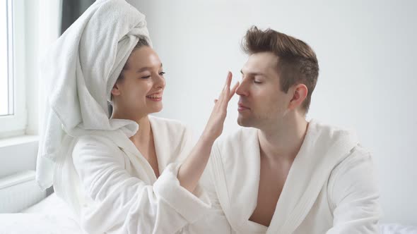 Tender Woman Takes Care of Man's Skin Applying Moisturizing Cream on Face Enjoy Beauty Procedures