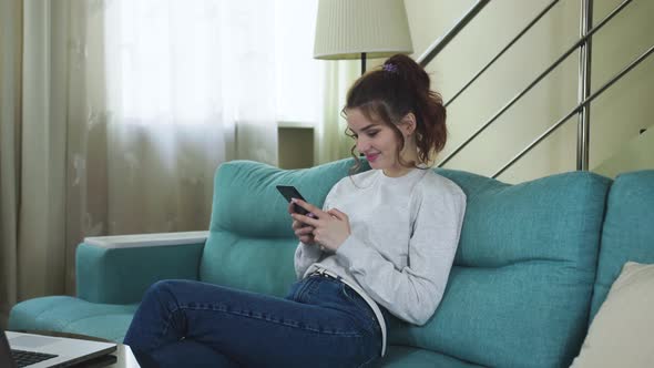 Relaxed Young Woman Using Smart Phone Surfing Social Media, Checking News, Playing Mobile Games alt