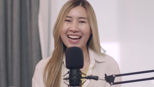 Asian female influencer recording a vlog using podcast microphone.