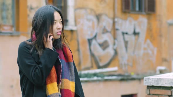 Relaxed Pretty young asian woman in the street talking by phone alt
