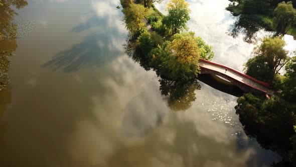 Public park romantic small walking bridge over pond located at green quiet scenery trees hanging ove alt