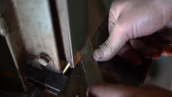 Sanding belt used to grind metal part for creating metal blade making sparks, Close up handheld shot alt