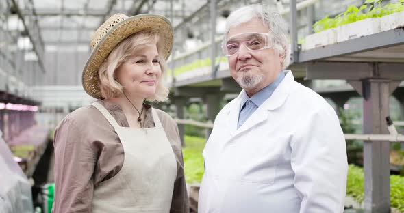Positive Caucasian Senior Man and Woman Looking at Each Other, Turning To Camera and Showing Thumbs alt
