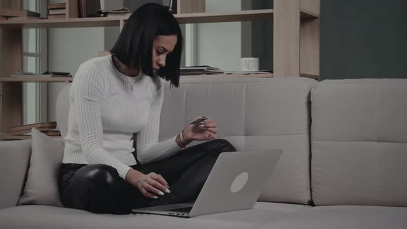 Black Woman Making Online Transaction On Sofa by azhorov | VideoHive
