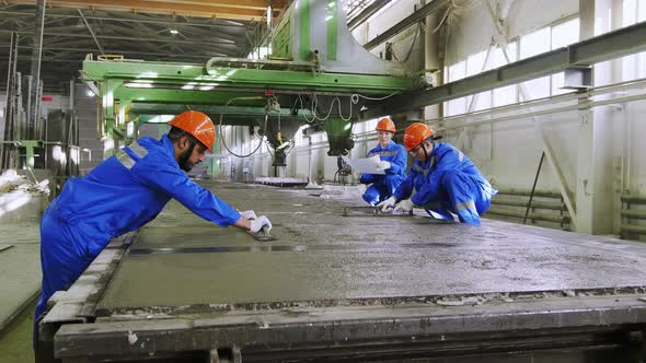 Factory workers leveling cement panel