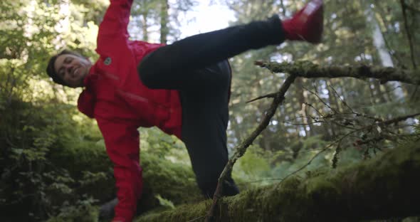 Young Man Jumping Over Felled Tree in Alaskan Forest on a Sunny Summer Day, Slow Motion Close Up Low alt