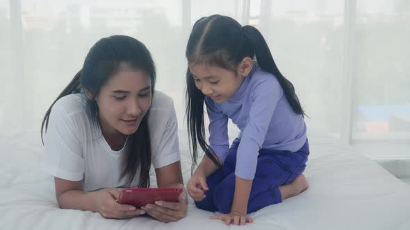 Young asian mother and little daughter looking tablet computer together for learning and education. alt