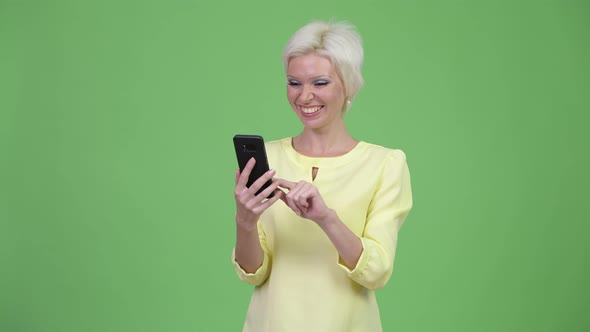 Happy Beautiful Businesswoman with Short Blond Hair Using Phone
