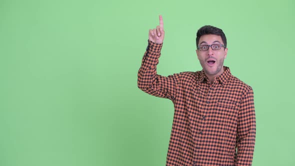 Happy Young Hispanic Hipster Man Pointing Up and Looking Surprised alt