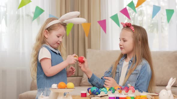 Little Girls with Rabbit Ears Play with Easter Eggs in Game of Who Will Break alt