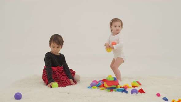 Toddler Girl Wearing Diaper and Her Sister Playing with Balls alt