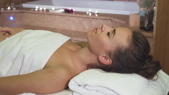 A Girl Enjoying Spa Treatments Looks Into the Camera and Smiles