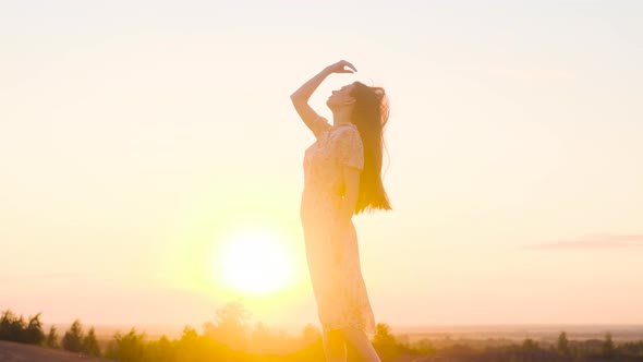 Slender Sexy Model Woman in White Long Dress Straight Her Hair and Stand on Top or Edge of Mountain alt