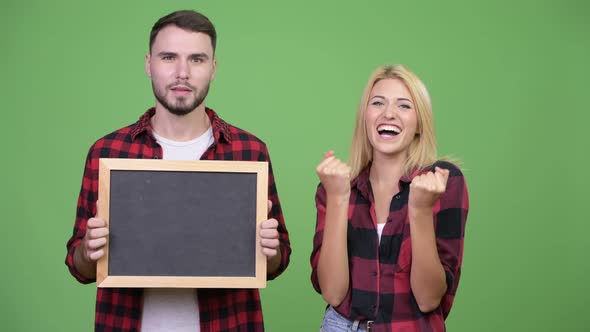 Young Couple Holding Blackboard and Looking Excited Together