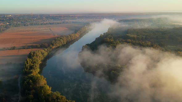 Aerial drone view of nature of Moldova at sunset. River and lush fog above it, village, greenery alt