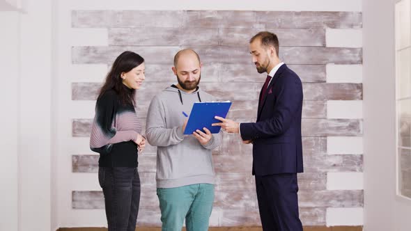 Real Estate Agent in Business Suit Giving Keys To Young Couple alt