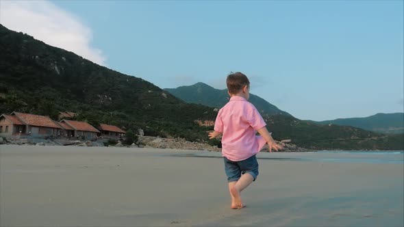 Happy Kid Running Along the beach.Silhouette of Children's Feet Walking on Wet Sand alt