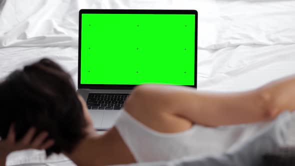 Laptop with Green Screen on Bed