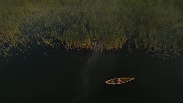 Wooden Boat with Fisherman on the Lake