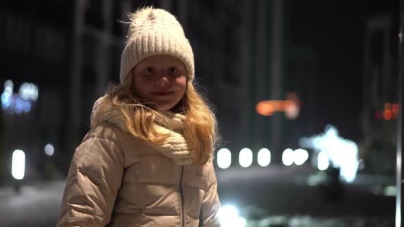 Beautiful Portrait of a Blonde Girl on a Christmas Decorated Street in Winter