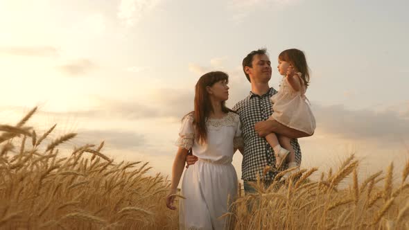 Farmer Dad and Mom Walk with Daughter in a Wheat Field. Child and Parent Are Playing. Happy Family alt