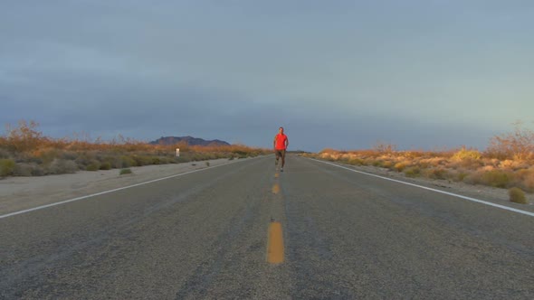 Male running along road at sunset alt