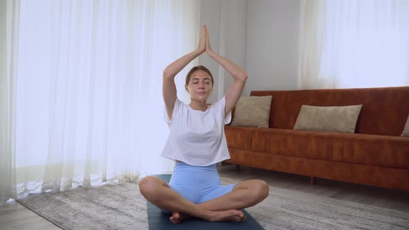 A Woman Meditates and Finishes Yoga Classes in the Lotus Position Namaste Over Her Head