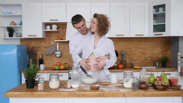 Happy Pregnancy, Family, Care, Cooking Together Concept. Pregnant Couple In Kitchen alt