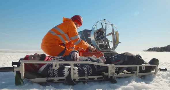 Paramedic Examining Unconscious Man Lying on Stretcher Outdoors in Winter alt