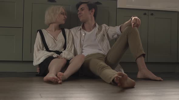 Young Couple in Love Sitting in the Kitchen Flirting and Drinking Wine alt