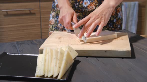 Slicing Goat Cheese With A Knife On Board