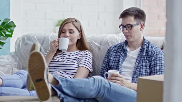 Young Couple Drinking Coffee on Sofa alt