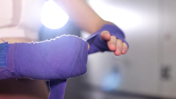 Girl Boxer Preparing for a Workout in the Gym She Rolls Bandages on Her Hands alt