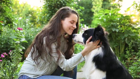 Smiling Young Attractive Woman Playing with Cute Puppy Dog Border Collie on Summer Outdoor alt
