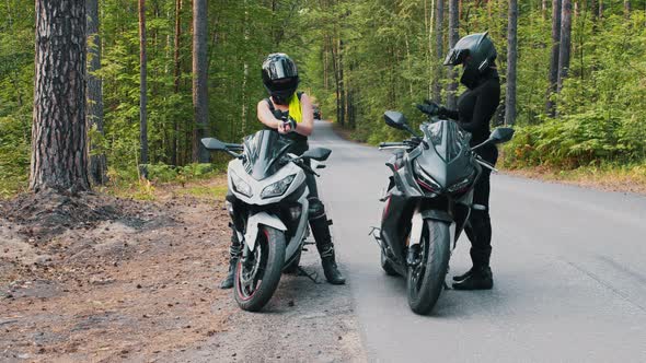 Women Friends Stands Up From the Motorbikes in the Forest alt