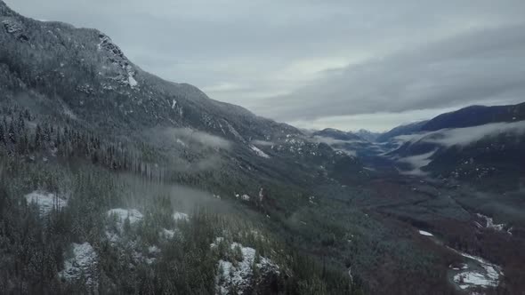 Wide aerial shot of a frozen cloudy valley in Vancouver Island, Canada alt