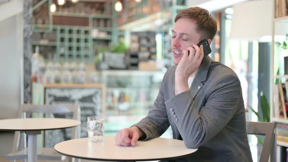 Young Man Talking on Phone in Cafe alt
