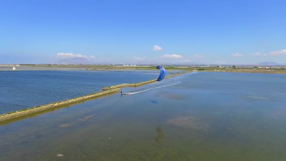 Aerial drone view of a man kiteboarding on a kite board. alt