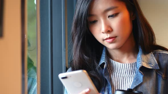 Businesswoman using smartphone beside a window at the office.