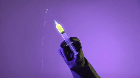 Doctor Pushes The Syringe Glowing With Liquid