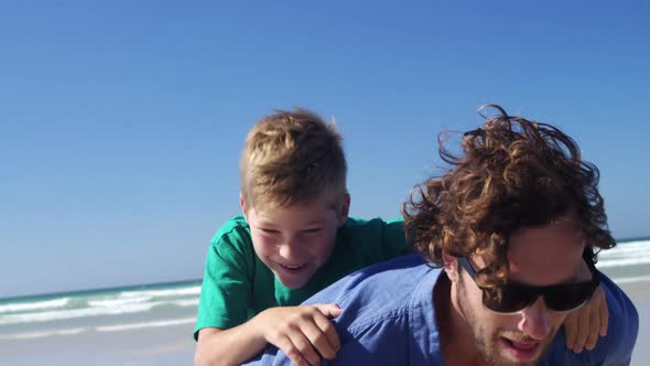 Father giving piggyback ride to his son at beach alt
