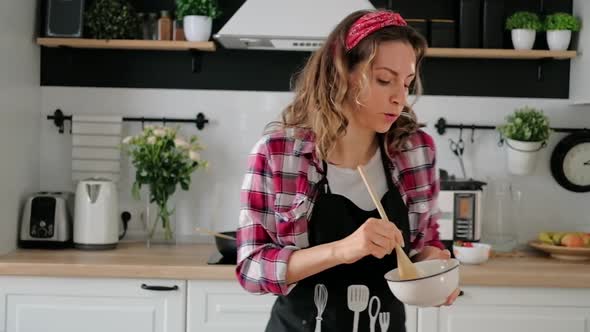 Carefree happy young woman housewife dancing alone cooking meal